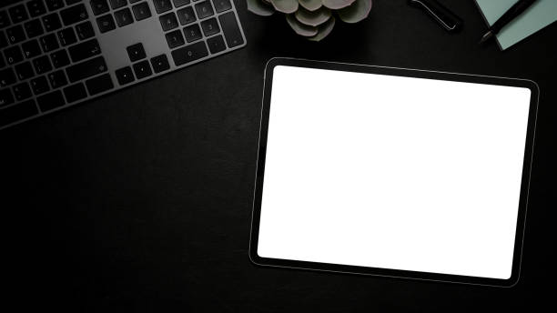 istock Modern office desk with tablet white screen mockup on black background. 1370409849