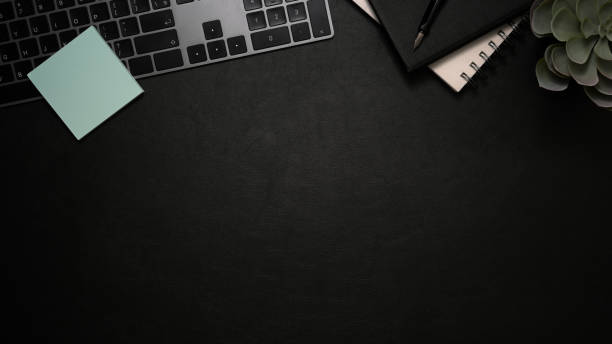 istock Hipster black office desk with keyboard, notebooks and copy space 1370409856