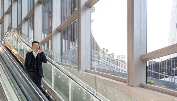 Business Executives using smart phone on the escalator