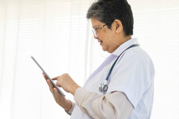 istock Confident senior female doctor using tablet computer in clinic. 1370412669