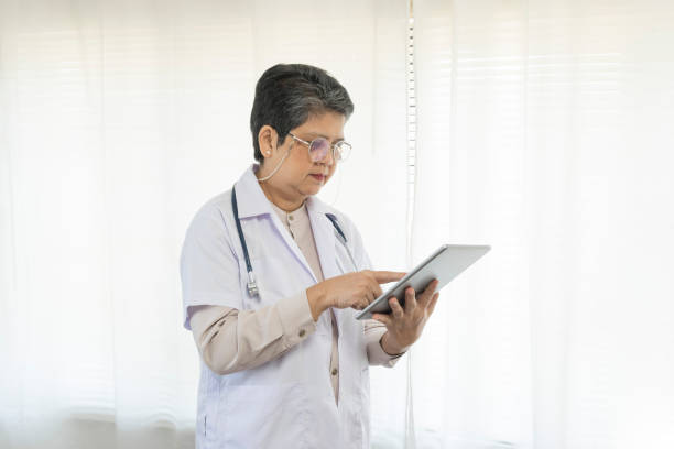 istock Confident senior female doctor using tablet computer in clinic. 1370412680