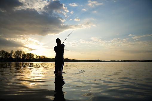 Silhouette young asian man fishing early morning