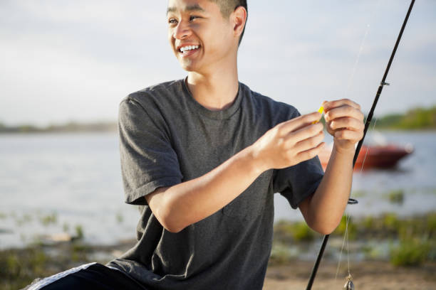 Happy young asian man putting on fishing bait