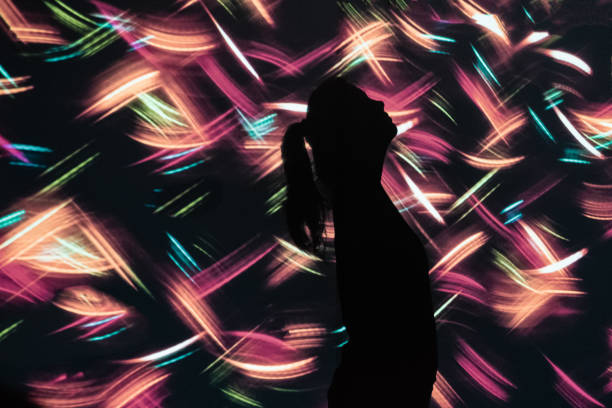 istock Young Woman Looking Up Against Colorful Abstract Light Background 1370412978