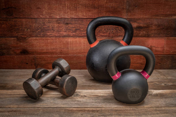iron kettlebells and a pair of dumbbells on a rustic wood background, exercise and fitness concept