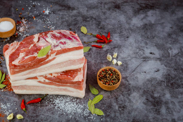 istock Fresh raw pork belly pieces on dark background with spices. 1370415564