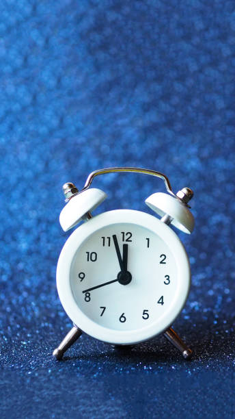 istock white alarm clock on a blue shiny background. copy space. 1370417657