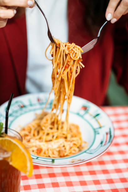 istock Woman in reed eats Italian spaghetti with fork. Close-up 1370418690