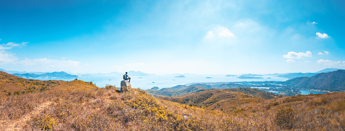 delighted hiking man siting on a rock, Mountain in Lantau Island, Hong Kong, alone outdoor, daytime