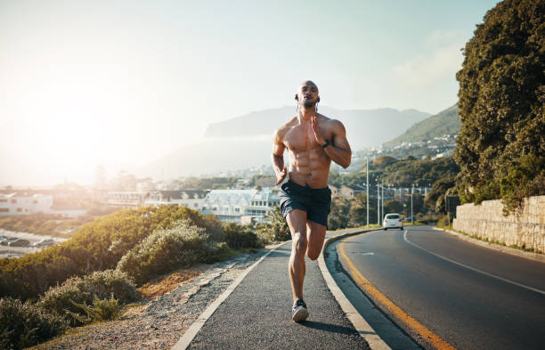 shot of a sporty young man running outdoors - atleta imagens e fotografias de stock