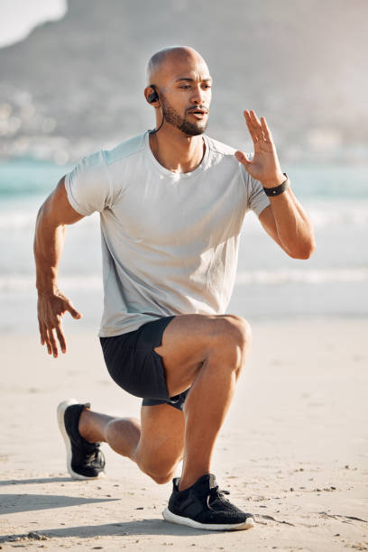 istock Shot of a young man doing lunges on the beach 1370421158
