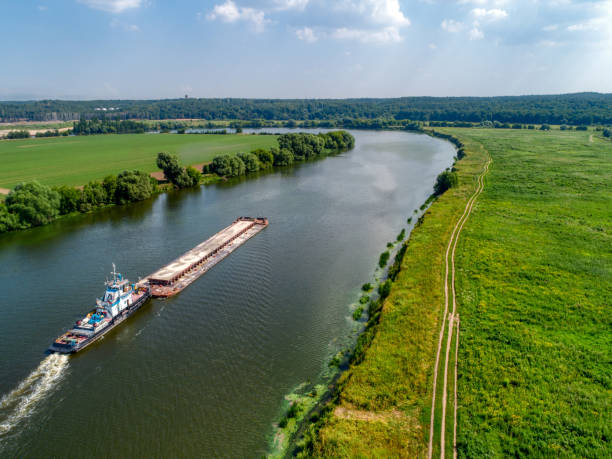 istock Towboat transports barge with sand along tranquil river 1370421234