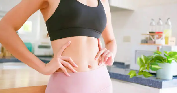 close up of asian woman shows her healthy body shape with confident in kitchen at home