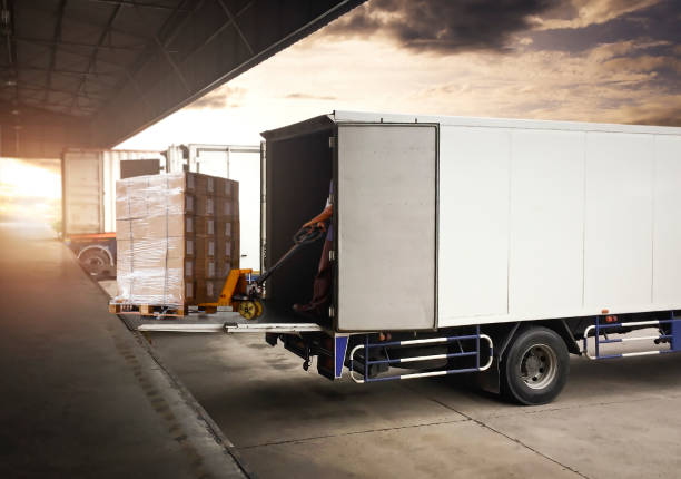 lavoratori che utilizzano il martinetto per pallet manuali che scaricano le scatole di imballaggio nel container di carico. consegna camion spedizione. camion che caricano al magazzino portuale. catena di approvvigionamento. magazzino spedizioni trasporto  - piattaforma di carico foto e immagini stock