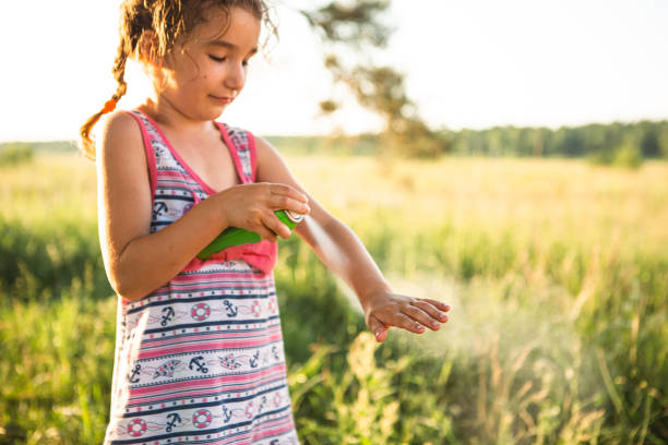 girl sprays mosquito spray on the skin in nature that bite her hands and feet. protection from insect bites, repellent safe for children. outdoor recreation, against allergies. summer time - mosquito child bug bite scratching imagens e fotografias de stock