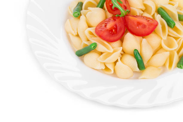 Italian shell pasta with tomatoes and beans. Whole background. It is located on a white surface. Close-up.
