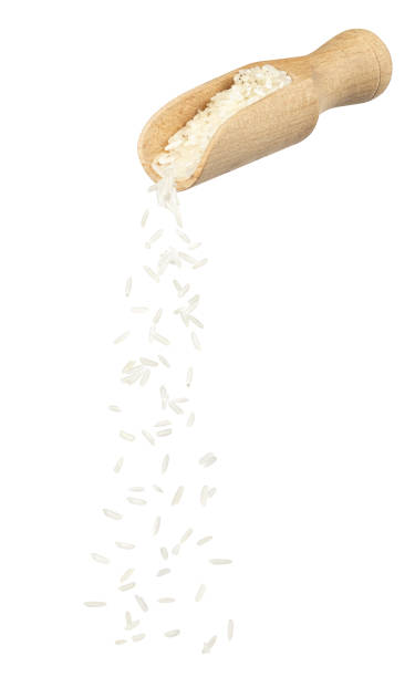 white rice falling from wooden scoop isolated stock photo