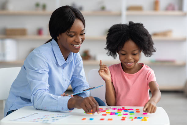 istock Cheerful black lady teaching little girl alphabet 1370433030