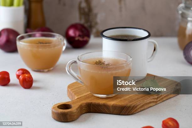 Homemade Bone Broth In Mugs With Spices On A Wooden Stick With Bay Leaf Tomatoes And Onions Stock Photo - Download Image Now