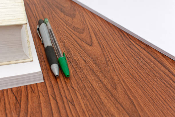 A notebook, paper, pen, highlighter, calculator and other other personal finance tools are seen scattered on a desk in this at home finance concept.