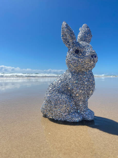 istock Silver sparkly glitter Easter Bunny at the beach.  Sitting on the sand at the waters edge. Blue ocean and sky in the background. Gold Coast Queensland Australia 1370435780