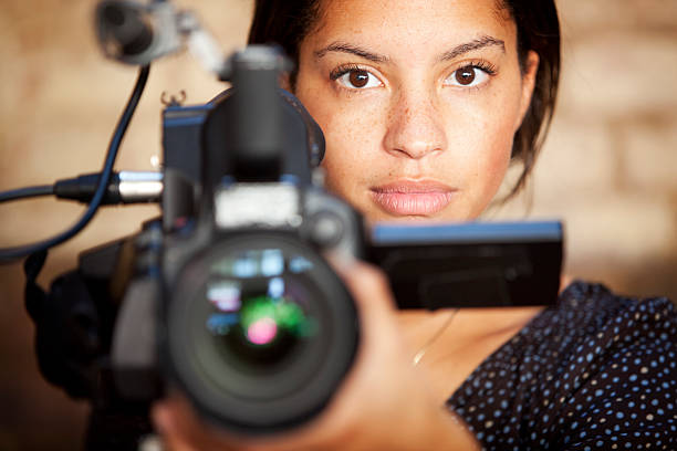 media: TV professional A confident glance from a video camera operator engaging eye contact with her subject during filming. camera man stock pictures, royalty-free photos & images