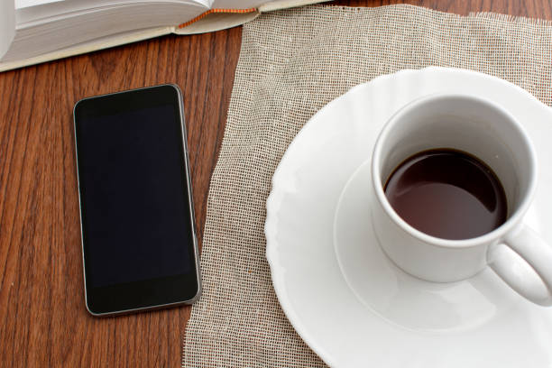 istock Cup of coffee and cell phone on wooden table. 1370437253