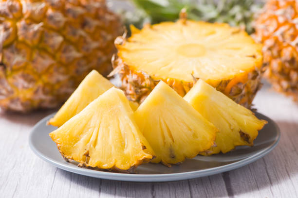 istock close up of pineapple with slices on wood table 1370440109