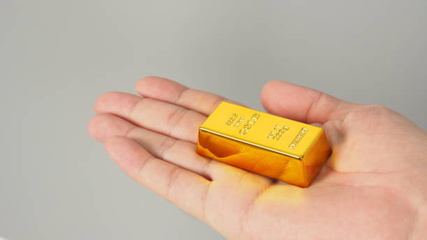 istock Gold bar in hand palm isolated on grey background. 1370440756