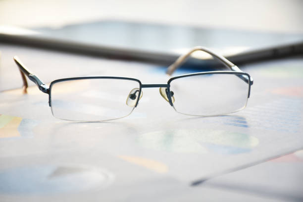 Eyeglasses and business finance documents and graphs on the desk