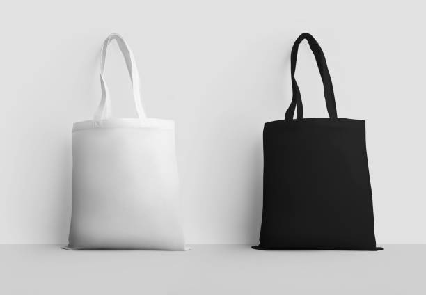 istock Mockup of a white, black totebag with a handle, sack 3d rendering, standing, isolated on a wall background. 1370443755