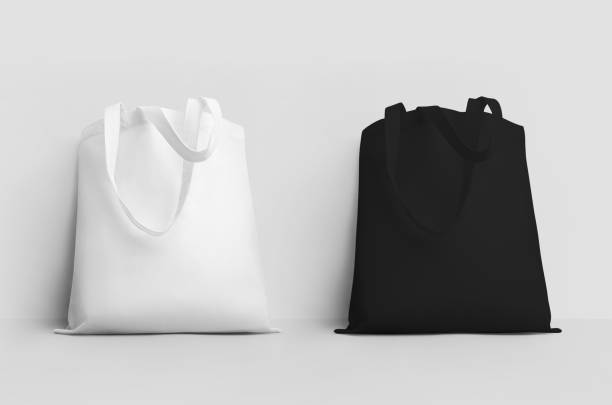 istock Mockup of a white, black totebag with a lowered handle, 3d rendering, standing, isolated on a wall background. 1370443798