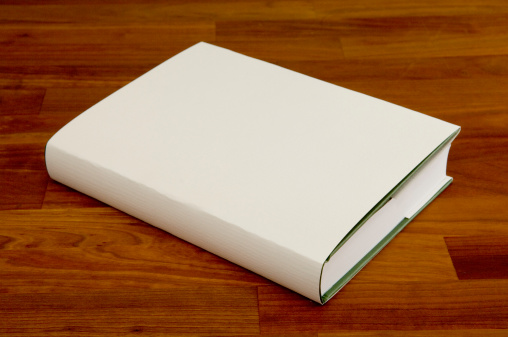 A book with blank cover, lying on a cherry wood table