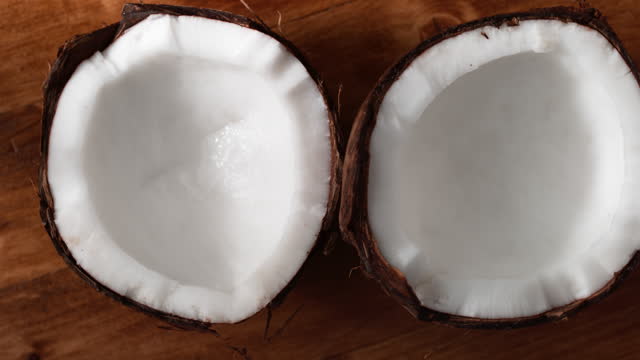 SLO MO LD Two coconut halves on a rotating wooden table
