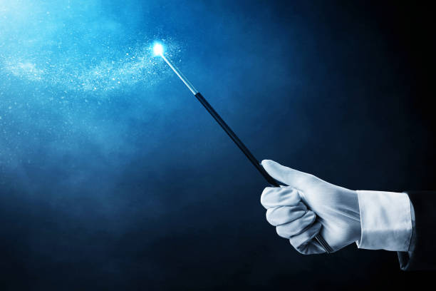 istock Magician hand holding magic wand on dark background 1370450346