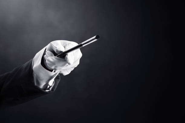istock Magician hand holding magic wand on dark background 1370450448