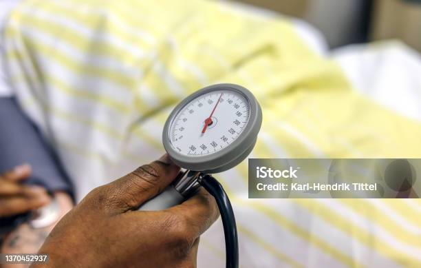 Colored female nurse is measuring the blood pressure of a patient lying in bed in a hospital - Selective Focus and much copyspace