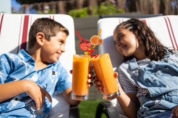 istock Two funny kids making a toast with orange juice 1370454547