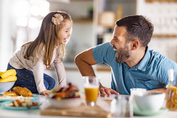 istock Cheerful single father and daughter having fun in dining room. 1370455385