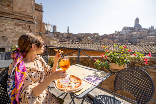 Young woman having lunch with pizza and wine at outdoor restaurant in Siena town stock photo