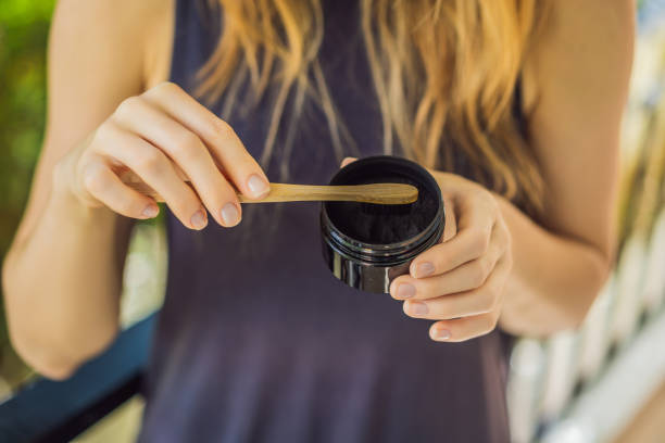 istock Young woman brush teeth using Activated charcoal powder for brushing and whitening teeth. Bamboo eco brush 1370458363