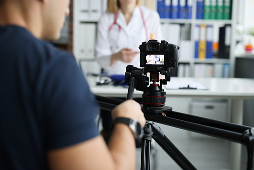 Fotógrafo filmando al médico en la cámara usando un primer plano de trípode y control deslizante photo