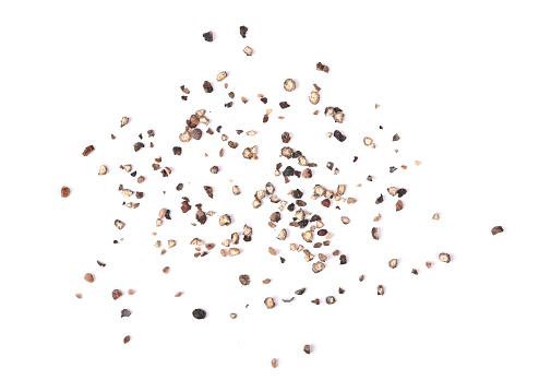 Black peppercorns falling on a pile close-up on a white background. Isolated