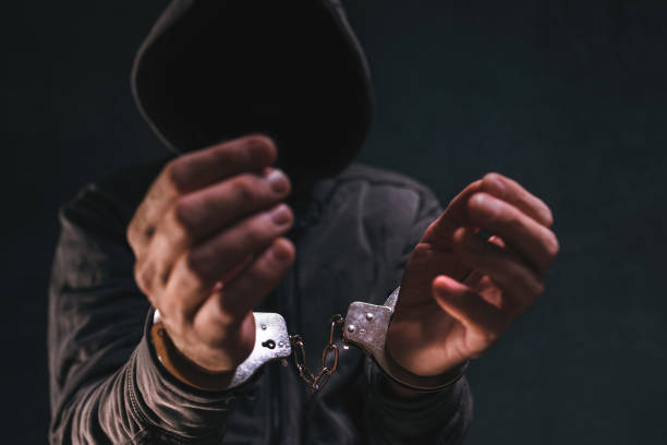 istock Handcuffed criminal with hoodie and obscured face 1370462555