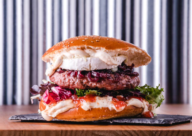 Big burger with goat cheese and tomato jam ready to eat. Fastfood concept Big burger with goat cheese and tomato jam ready to eat. Fastfood and unhealthy food concept. spanish hamburger stock pictures, royalty-free photos & images