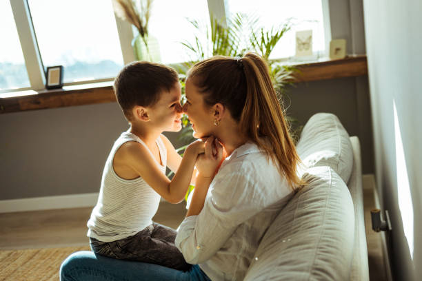 istock Single mom tenderly embracing little son while sitting on cozy couch 1370462877