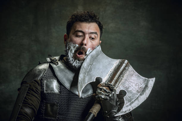 komiczny portret średniowiecznego wojownika lub rycerza z brudną zranioną twarzą golącą się z siekierą odizolowaną na ciemnym tle vintage. porównanie epok, historii, piękna - ancient weapon audio zdjęcia i obrazy z banku zdjęć