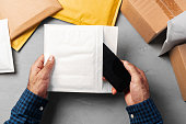 Male hands packing bubble envelopes for shipping.