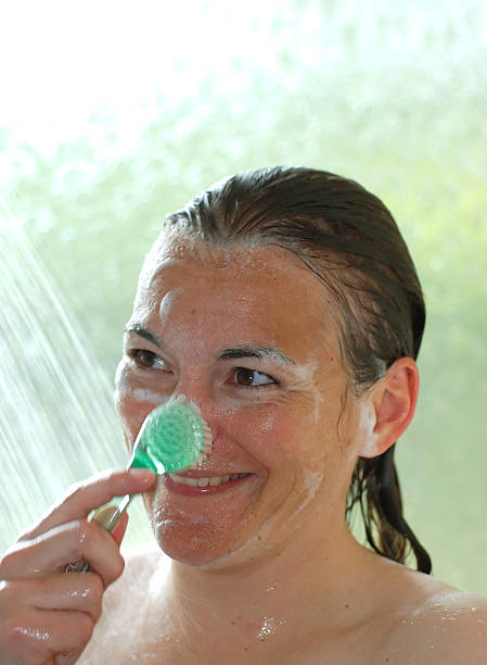 wash face 3 Girl washes her face in the shower using a facial brush shower women falling water human face stock pictures, royalty-free photos & images