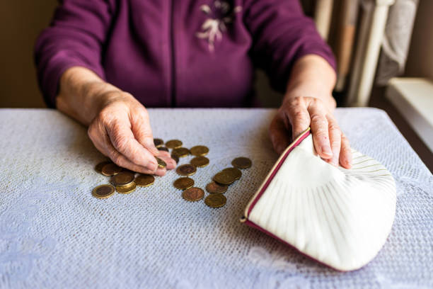 vecchia donna seduta miseramente a casa e contando le monete rimanenti della pensione nel suo portafoglio dopo aver pagato le bollette. - miseramente foto e immagini stock